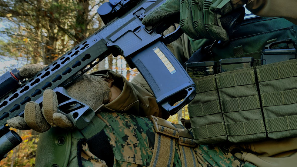 Soldier holding a rifle with a plastic magazine, showcasing plastic solutions for the military